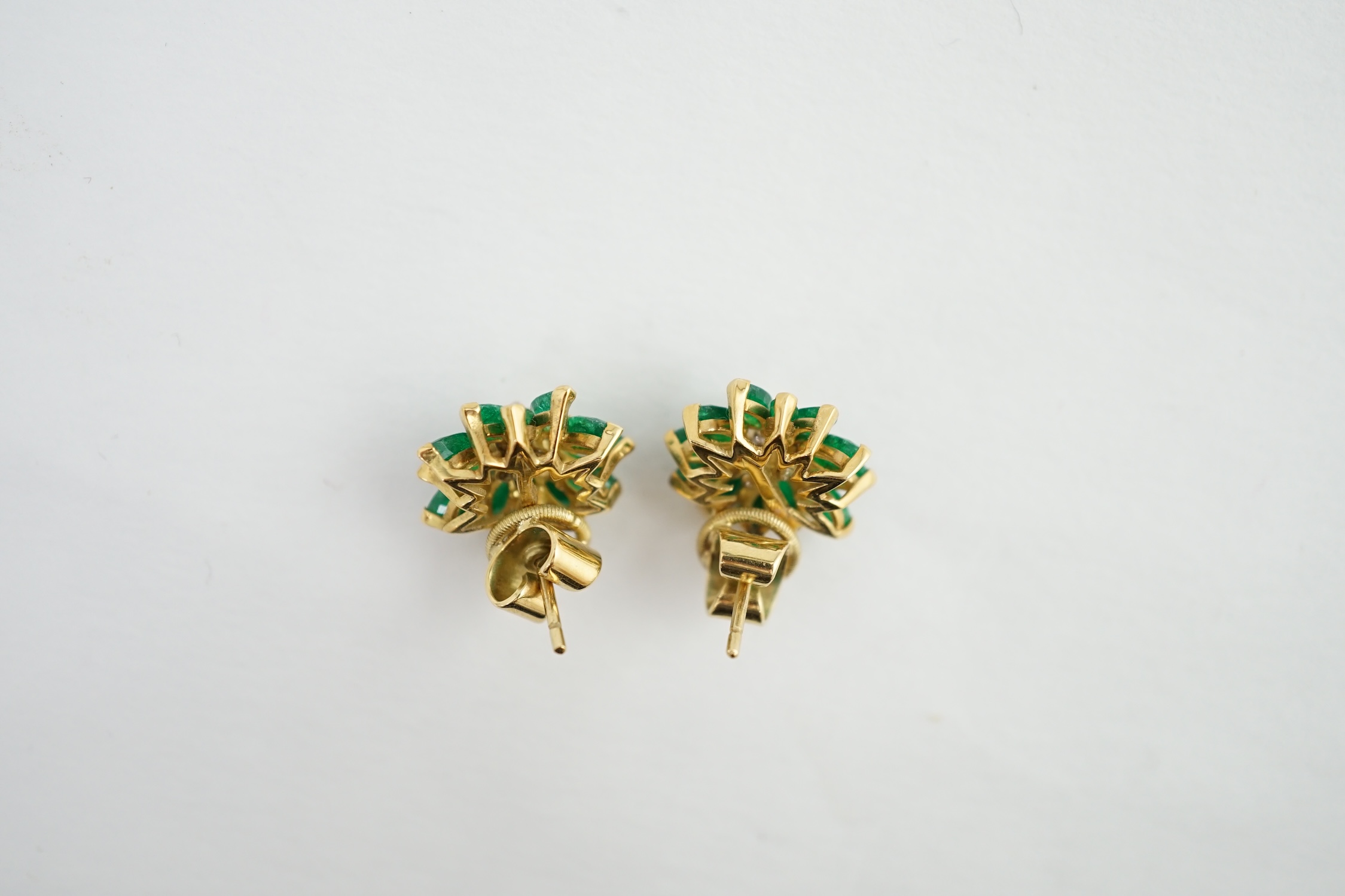 A modern pair of yellow metal, emerald and diamond set flowerhead stud earrings, 13mm, gross weight 6.4 grams. Condition - poor